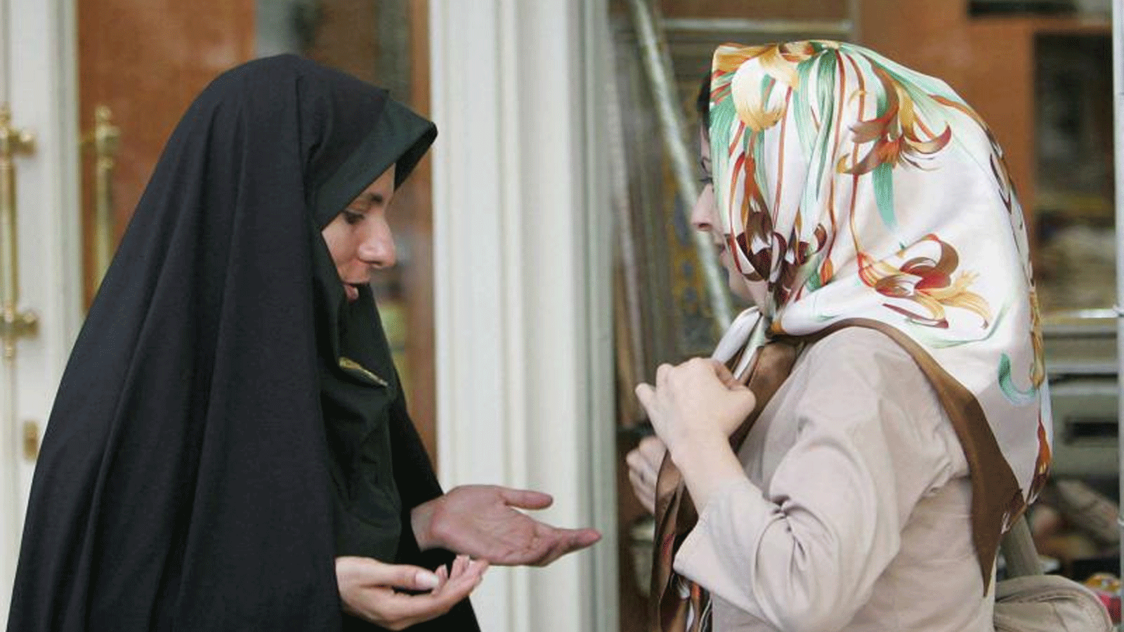 شرطية إيرانية تتحدث مع امرأة بخصوص ملابسها خلال حملة قمع لفرض قواعد الزي الإسلامي في طهران