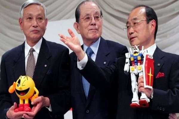 ماسايا ناكامورا (في منتصف الصورة) مع نائب رئيس شركة نامكو كوشيرو تاكاغي (إلى يسار الصورة) ومدير الشركة تاكيو تاكاسو في صورة جمعتهم عام 2005 