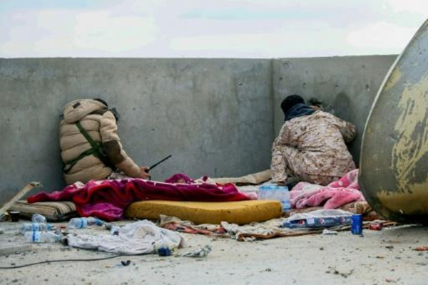 مقاتلان مواليان لحكومة الوفاق الوطني المعترف بها دوليًا يراقبان محيطهما من على سطح مبنى في جنوب طرابلس في 12 يناير 2020