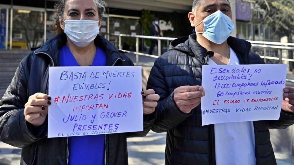 عاملون في القطاع الصحي يرفعون لافتات كتب عليها 