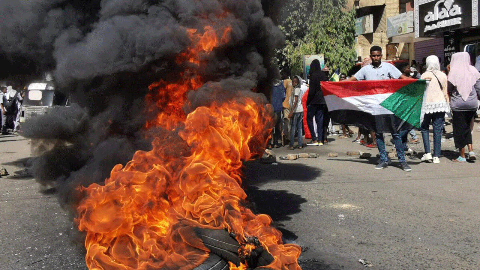 متظاهرون سودانيون يمرون بالقرب من الإطارات المحترقة أثناء تجمعهم للاحتجاج على الانقلاب العسكري