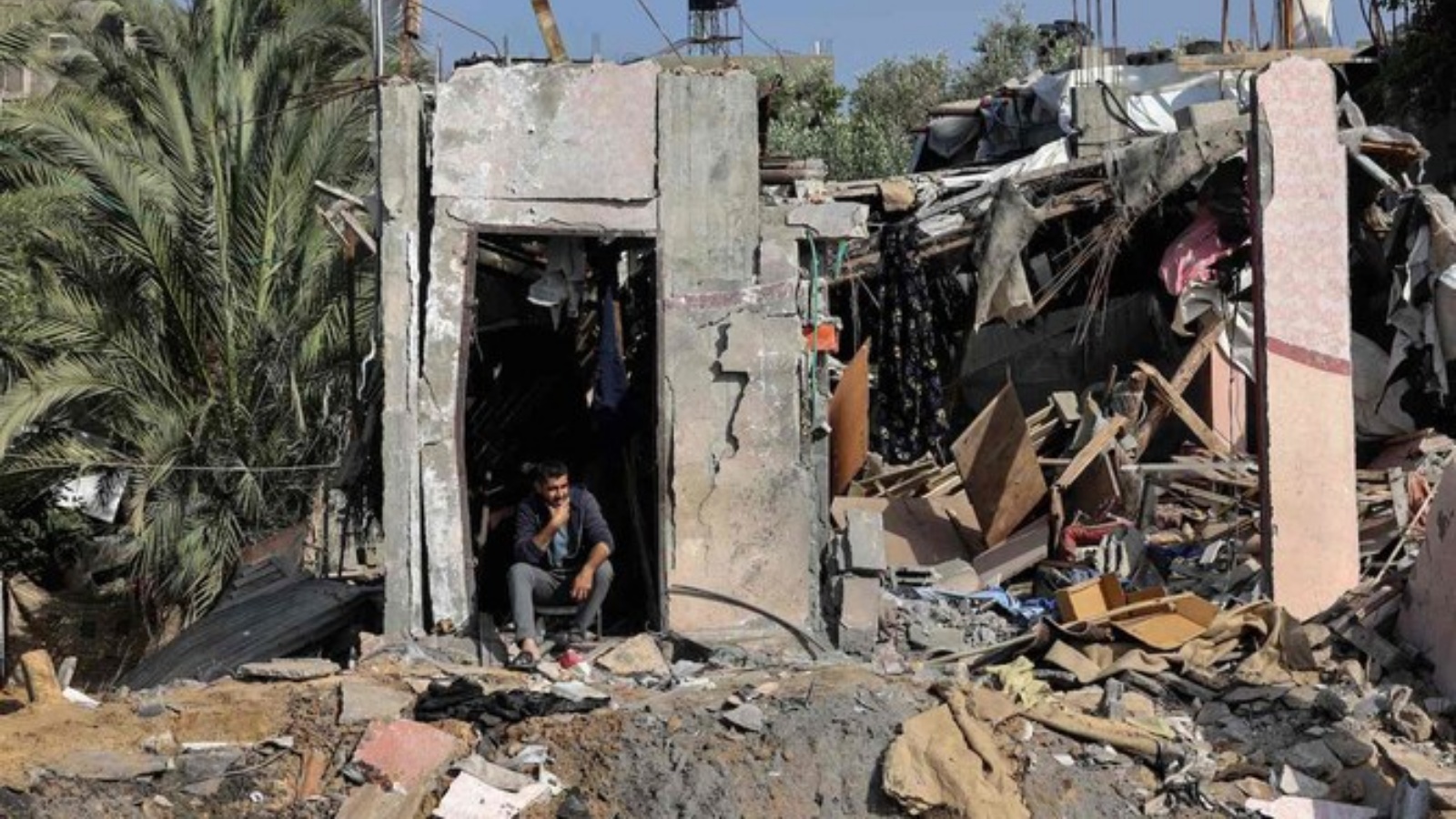 فلسطينيون يتفقدون ممتلكاتهم وسط أنقاض منزلهم في مخيم النصيرات في غزة، 14 مايو 2023، وسط وقف لإطلاق النار