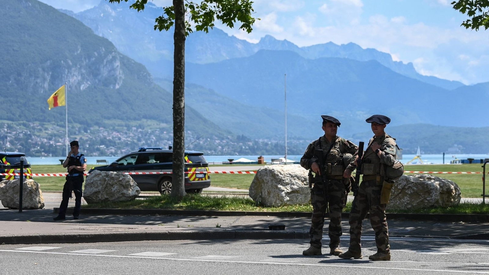 ضابط شرطة فرنسي وعنصر من قوة المشاة الجبلية يقفان بالقرب من البحيرة في آنسي، بعد حادثة الطعن الجماعي 8 يونيو 2023