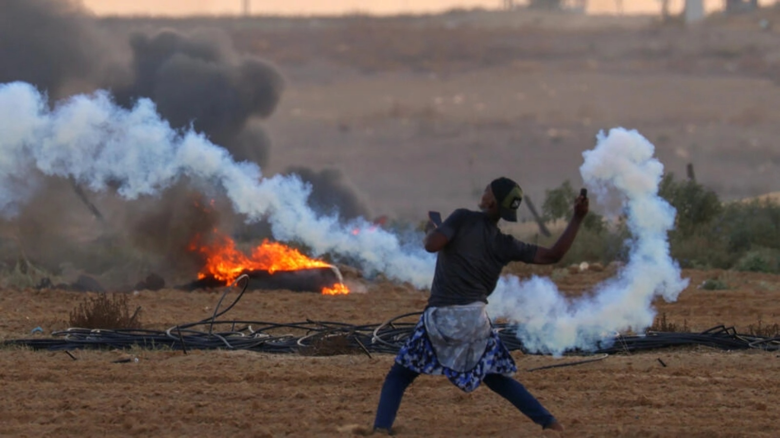 متظاهر فلسطيني يعاود رمي قنبلة مسيلة للدموع اطلقتها القوات الإسرائيلية على الحدود مع قطاع غزة 