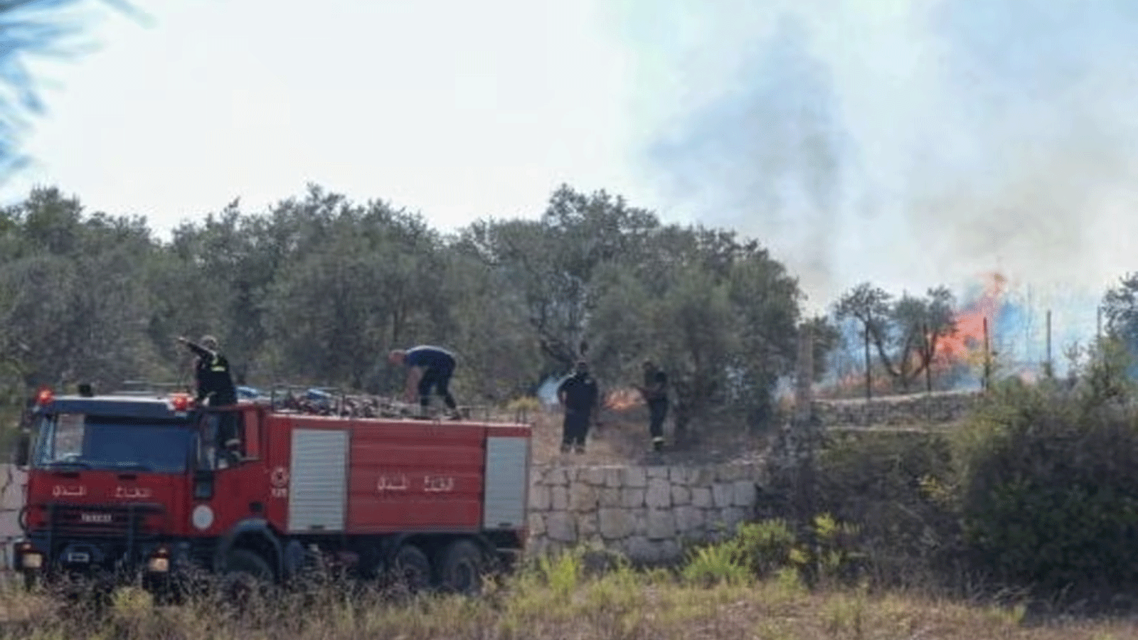 عمال الدفاع المدني ورجال الإطفاء اللبنانيون يقومون بإخماد حريق غابة ورد أنه اندلع بعد إطلاق قذيفة من إسرائيل في علما الشعب، بالقرب من حدود جنوب لبنان مع إسرائيل في 26 أكتوبر/تشرين الأول 2023
