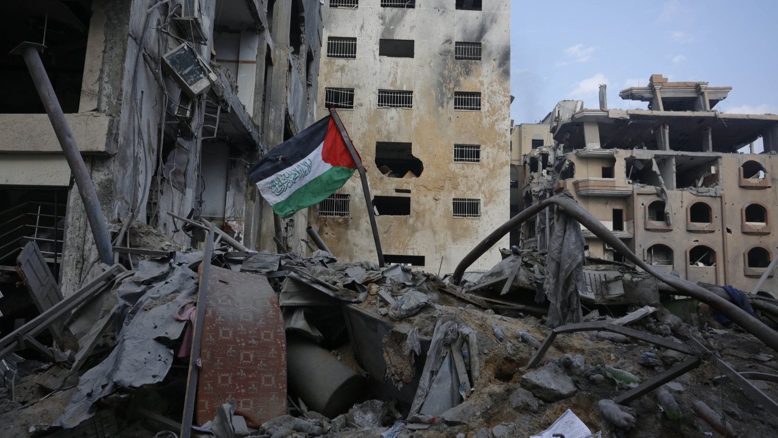 علم فلسطيني على أنقاض مبنى دمرته غارات جوية إسرائيلية في حي الرمال بمدينة غزة، في 10 أكتوبر 2023