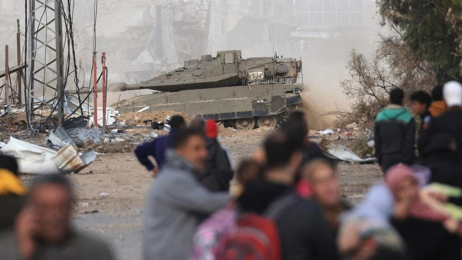 مدرعة إسرائيلية تمر أمام فلسطينيين فارين من القصف على غزة على طريق صلاح الدين في حي الزيتون