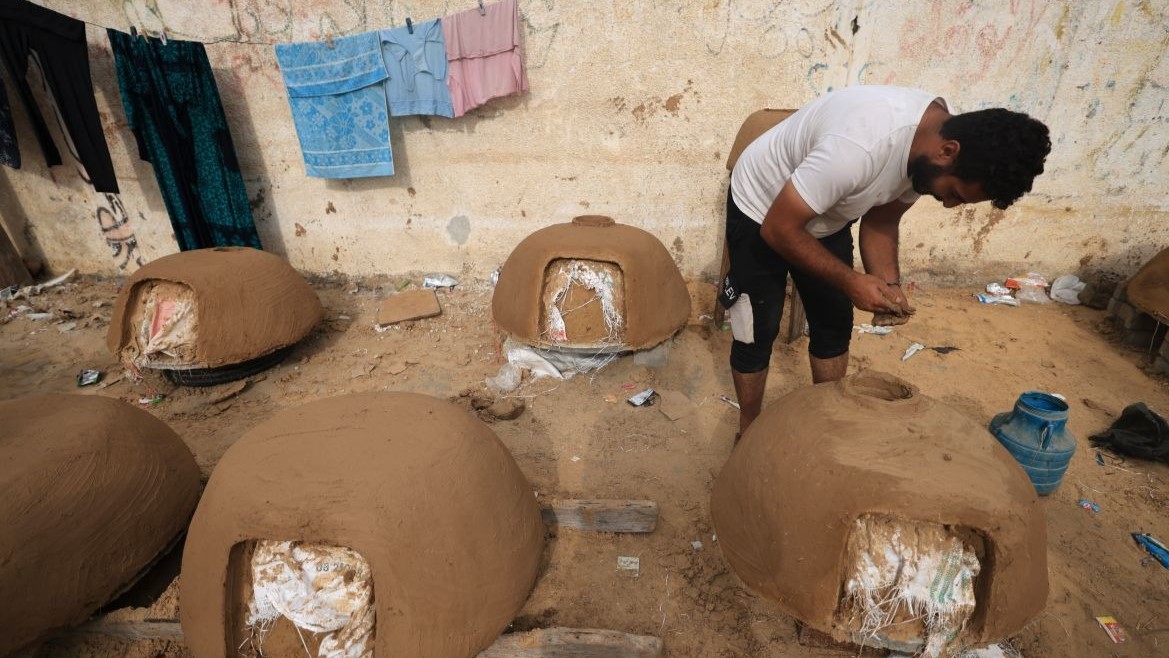 رجل فلسطيني يصنع الطين أثناء صنع أفران الطابون التقليدية التي يبيعها بمبلغ 25 دولارًا، مع ندرة إمدادات تشغيل مواقد الغاز، في خان يونس جنوب قطاع غزة