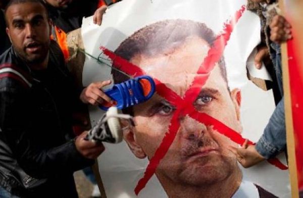 متظاهرون في لندن يضربون صورة للأسد بأحذيتهم- أ ف ب 