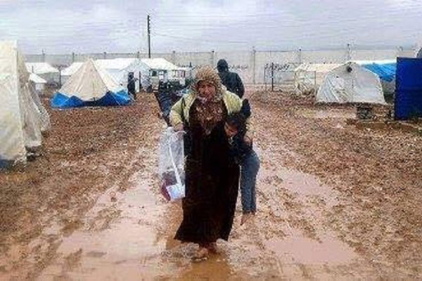 عراقية تحمل طفلها وحاجياتها في مخيم للنازحين