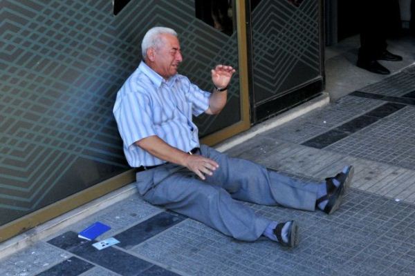 رجل يوناني ينتظر أمام أحد المصارف في محاولة لسحب المال