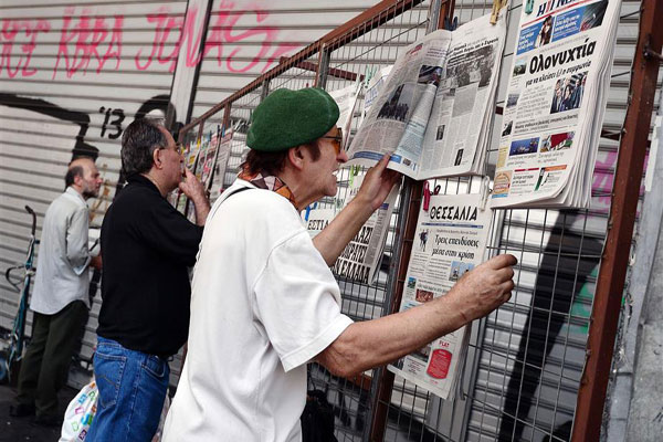 متابعة عناوين الصحف في أحد شوارع اثينا (أ ف ب)