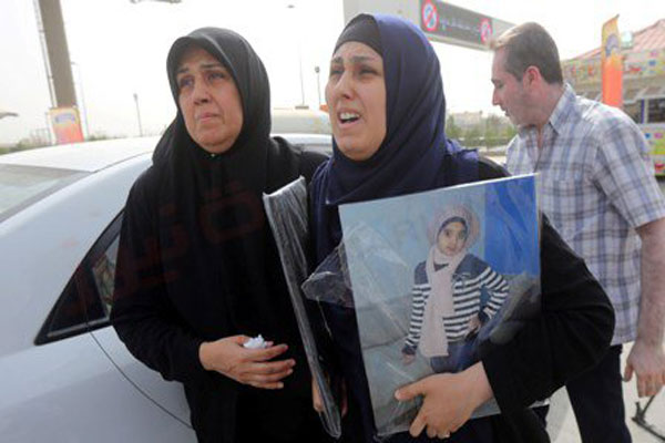 والدة الطفلين العراقيين الغريقين تحمل صورتيهما