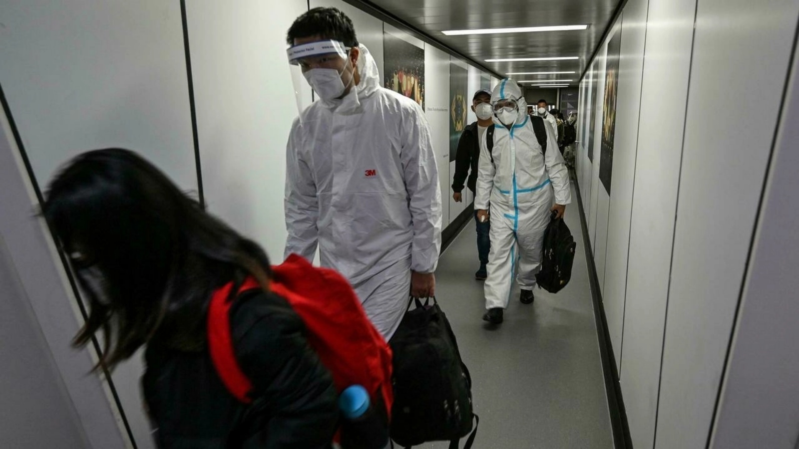 ركاب، بعضهم يرتدي معدات الحماية الشخصية الكاملة، ينزلون من طائرتهم في مطار بودونغ الدولي في شنغهاي في 18 يناير 2022
